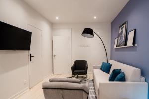 ein Wohnzimmer mit einer weißen Couch und einem Stuhl in der Unterkunft SUITE APOLLINAIRE : au cœur de la Rive Gauche, neuf, design, 2/4 personnes in Paris