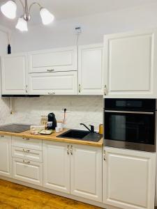 a kitchen with white cabinets and a black microwave at A&C Hotel Rooms - Up in the Sky in Oradea