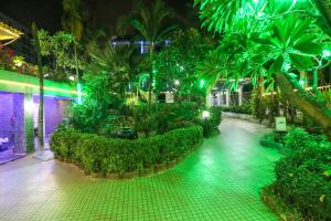 a building with a garden with palm trees and lights at Natural Beach Hotel Pattaya in Pattaya Central