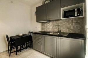 eine Küche mit einer Spüle, einem Tisch und einer Mikrowelle in der Unterkunft Accogliente Bussana 1 in Sanremo