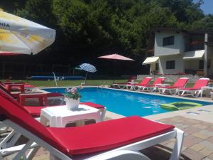 布雷佐伊Casuta Didi的一个带红色和白色椅子和遮阳伞的游泳池