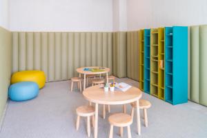 a room with two tables and stools and green shelves at Hotel Verde Mar & SPA in Ribeira Grande