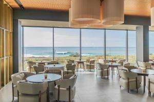 a restaurant with tables and chairs and a view of the ocean at Hotel Verde Mar & SPA in Ribeira Grande