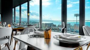 a dining room with a table and chairs and windows at Hotel Verde Mar & SPA in Ribeira Grande