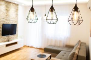 a living room with three lights hanging from the ceiling at Reset Apartment in Novi Sad