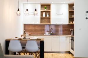 a kitchen with white cabinets and a table with chairs at Reset Apartment in Novi Sad