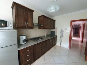 a kitchen with wooden cabinets and a white refrigerator at APARTMENT AYOUB -for families only- in Nador