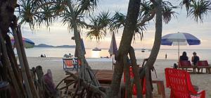 a beach with chairs and umbrellas and palm trees at MOOK BOONCHU HOTEL in Koh Mook