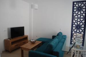 a living room with a blue couch and a tv at Apartamentos Costa de la Luz playa in Rota