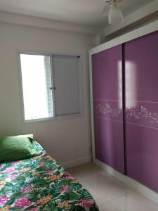 a bedroom with a purple bed and a window at Apto em santos 900 m praia in Santos