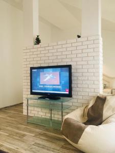 uma sala de estar com televisão numa parede de tijolos em Comfort place in the city centre em Ivano-Frankivsʼk