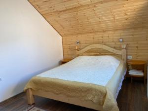 Cama en habitación con techo de madera en Pensiunea Casa Alexandra en Vatra Dornei