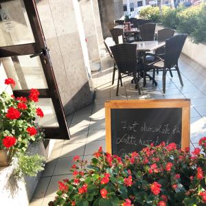 a restaurant with a sign on a patio with red flowers at Continental Forum Tirgu Mures in Târgu-Mureş