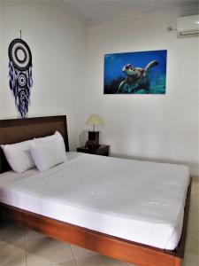 1 dormitorio con 1 cama y una pintura en la pared en La Bila Dive Resort Amed en Amed