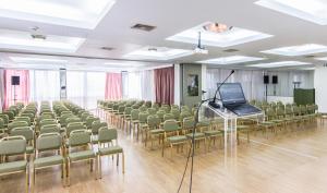 a room with chairs and a laptop on a podium at Hotel Metropol in Larisa