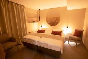 1 Schlafzimmer mit einem großen Bett und 2 Stühlen in der Unterkunft B-Lodge Boutique Hôtel in Louvain-la-Neuve