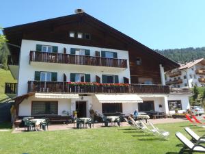 a building with a balcony and tables and chairs at Albergo Somont in Ortisei