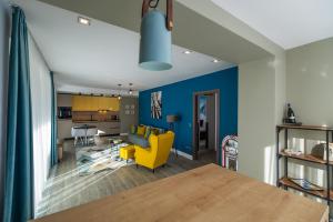 a living room with a yellow chair and a blue wall at Mariah Spa Deluxe Apartment in SILVER MOUNTAIN in Poiana Brasov