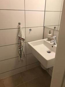 a white bathroom with a sink and a mirror at Gemütliches Ferienhaus hinterm Deich in Nordstrand