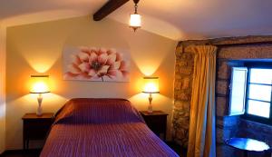 a bedroom with a bed and two lamps and a window at CASA DO CASTELLO MONSANTO in Monsanto