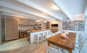 een keuken met een houten tafel en witte stoelen bij Driftwood by The Oyster Collection in Kenton on Sea