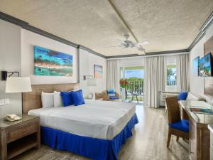 a hotel room with a bed and a desk and a window at Coconut Court Beach Hotel in Bridgetown