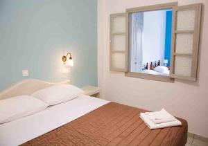 Schlafzimmer mit einem Bett mit einem Spiegel und einem Fenster in der Unterkunft Sail Inn Studios & Apartments in Kamari