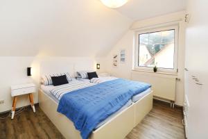 a white bedroom with a large bed with blue sheets at Fewo Sommergarten 4022_CLEM in Ostseebad Karlshagen