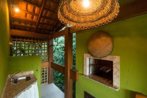 a kitchen with a green wall with a fireplace at Pousada Vila do Bosque in Bombinhas
