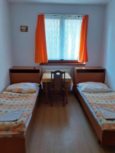 two beds in a room with a table and a window at Ubytovňa Tavros in Žilina