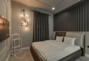 Schlafzimmer mit einem Bett mit weißer Bettwäsche und einem Fenster in der Unterkunft Green Palace Hotel in Yerevan
