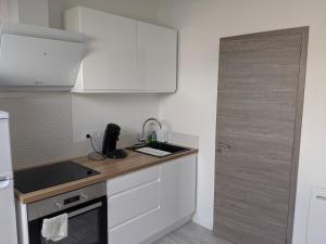 a kitchen with white cabinets and a sink and a door at Beau Studio Centre Ville Paul Bert in Valence