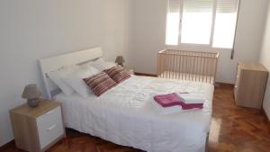 een slaapkamer met een wit bed met twee boeken erop bij Apartamento Vila Nova in Ponta Delgada