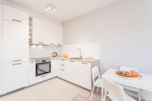 ワルシャワにあるChill Apartments Jana Kazimierzaの白いキャビネット、テーブルと椅子付きのキッチンが備わります。