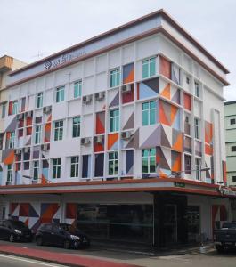 een gebouw met een kleurrijke gevel waar auto's voor geparkeerd staan bij Walk In Hotel in Kota Kinabalu