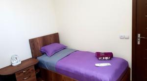ein kleines Bett mit violetter Bettwäsche und einem Telefon darauf in der Unterkunft Guest house Jangulashvili in Sighnaghi
