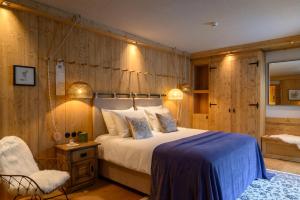 a bedroom with a large bed and a chair at Boutique hotel Vila Planinka in Zgornje Jezersko