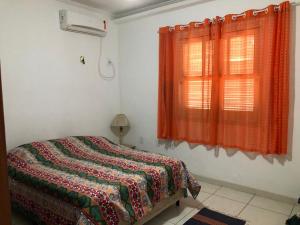 um quarto com uma cama e uma janela com cortinas laranja em Flats Paraty em Paraty