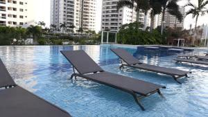 2 tumbonas en una piscina con edificios en Ilha Pura Barra Temporada, en Río de Janeiro