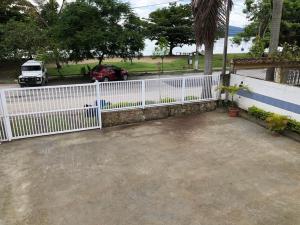 a white fence with a car parked in a driveway at Flats Paraty in Paraty