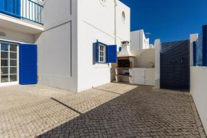 a white house with blue doors and a courtyard at Blue Villa by ALGARVEMANTA in Manta Rota