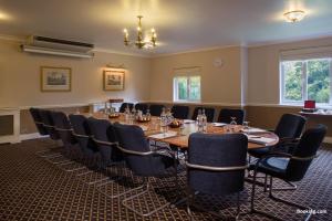 una sala de conferencias con una mesa larga y sillas en Audleys Wood Hotel, Basingstoke en Basingstoke