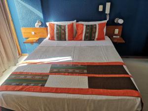 1 dormitorio con 1 cama grande con almohadas de color naranja en Hotel Esmeralda, en Iquique