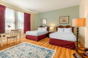 a hotel room with two beds and a desk at The Carriage House Inn Newport in Middletown