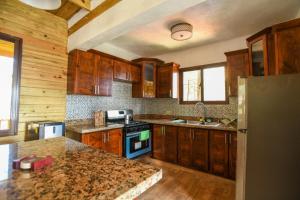 - une cuisine avec des placards en bois et un plan de travail en granit dans l'établissement Rancho Batlle, à Jarabacoa