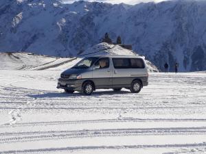 a van is driving on a snow covered road at Sweet night in Kazbegi