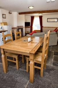 une table et des chaises en bois dans un salon dans l'établissement DAIRY MAIDS COTTAGE, à Seascale