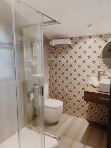 a bathroom with a toilet and a glass shower at La Fuentona de Santillana in Santillana del Mar