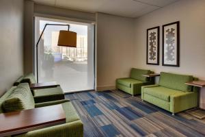 Holiday Inn Express Baltimore BWI Airport West, an IHG Hotel في هانوفر: غرفة انتظار مع كرسيين اخضر وطاولة