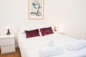 sypialnia z białym łóżkiem z czerwonymi poduszkami w obiekcie MyCityHaven The KingsWeston - flexible home sleeps 7 w Bristolu